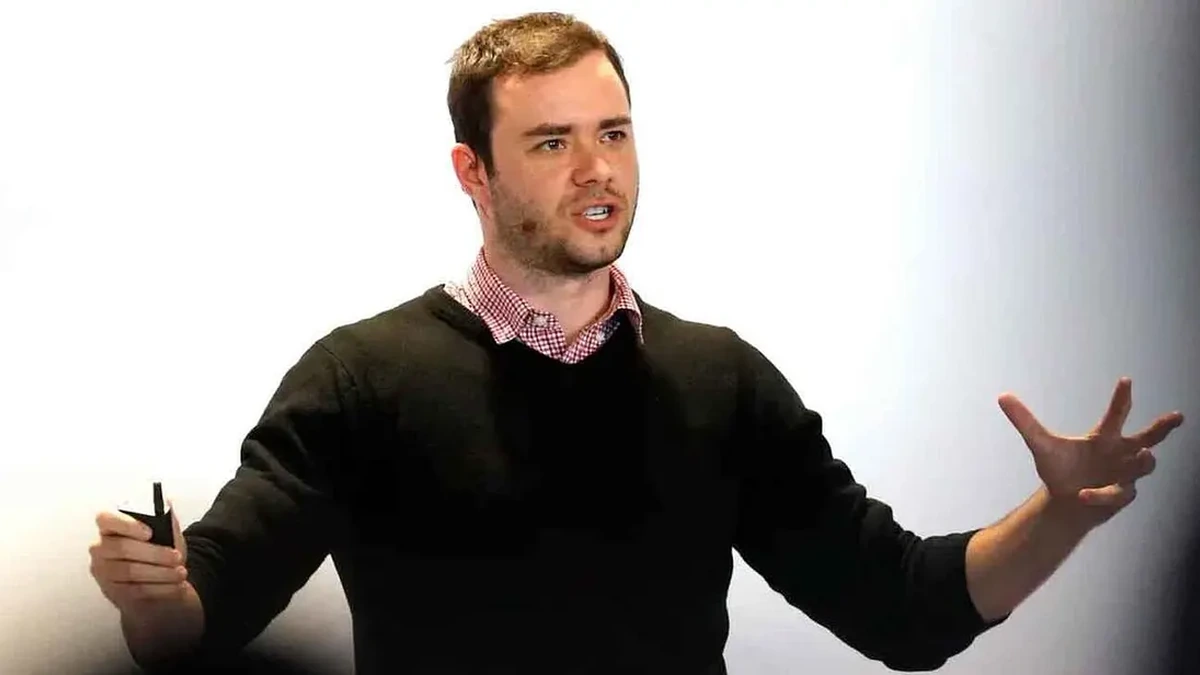 Andrej Karpathy, OpenAI co-founder and AI researcher, speaking on stage in a black sweater against a white background